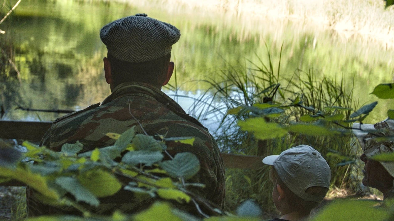 Homme avec casquette de dos face à un petit lac